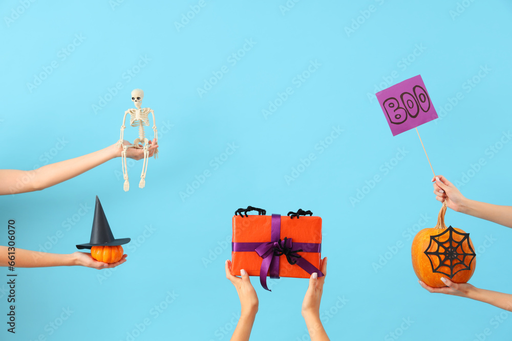 Fototapeta premium Women with Halloween gifts, pumpkins and decor on blue background