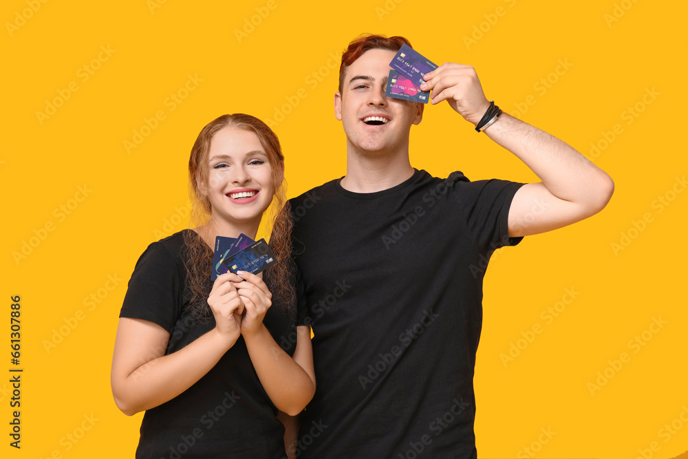 Young couple with credit cards on yellow background Young couple with credit cards on yellow background