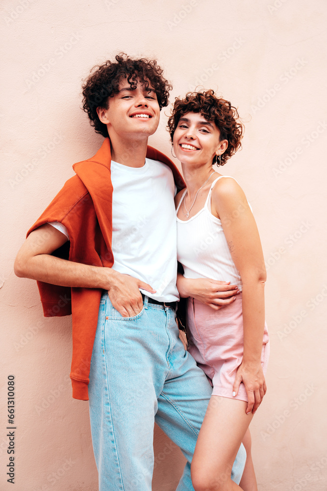 Young smiling beautiful woman and her handsome boyfriend in casual summer white t-shirt and jeans clothes. Happy cheerful family. Female having fun. Couple posing in the street near wall
