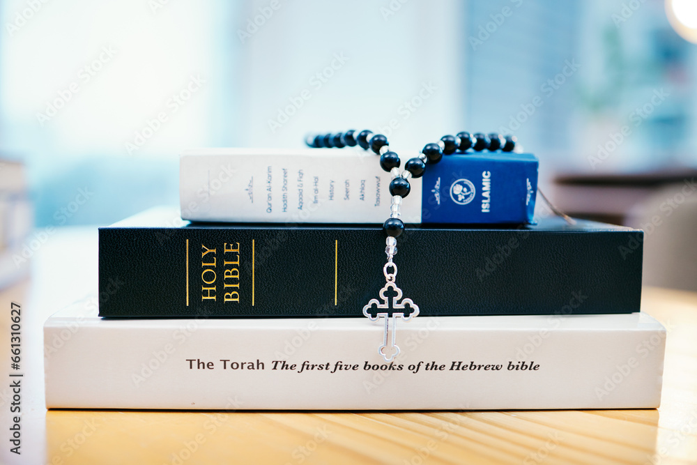 Books, stack and closeup on table for faith, Abrahamic religion or rosary with crucifix for study in home. Knowledge, holy spirit and education with cross for Jesus, Muhammad or Moses with solidarity - obrazy, fototapety, plakaty 
