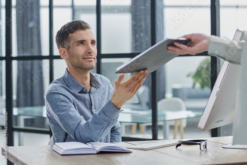 Focus on male hands passing each other folder with papers photo