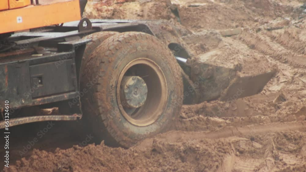Wheels in the mud and clay of an excavator that digs a hole, close-up. Industry