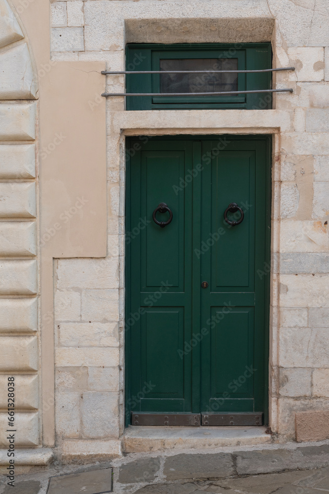 Old door with metal knocker surrounded by hand-crafted marble blocks