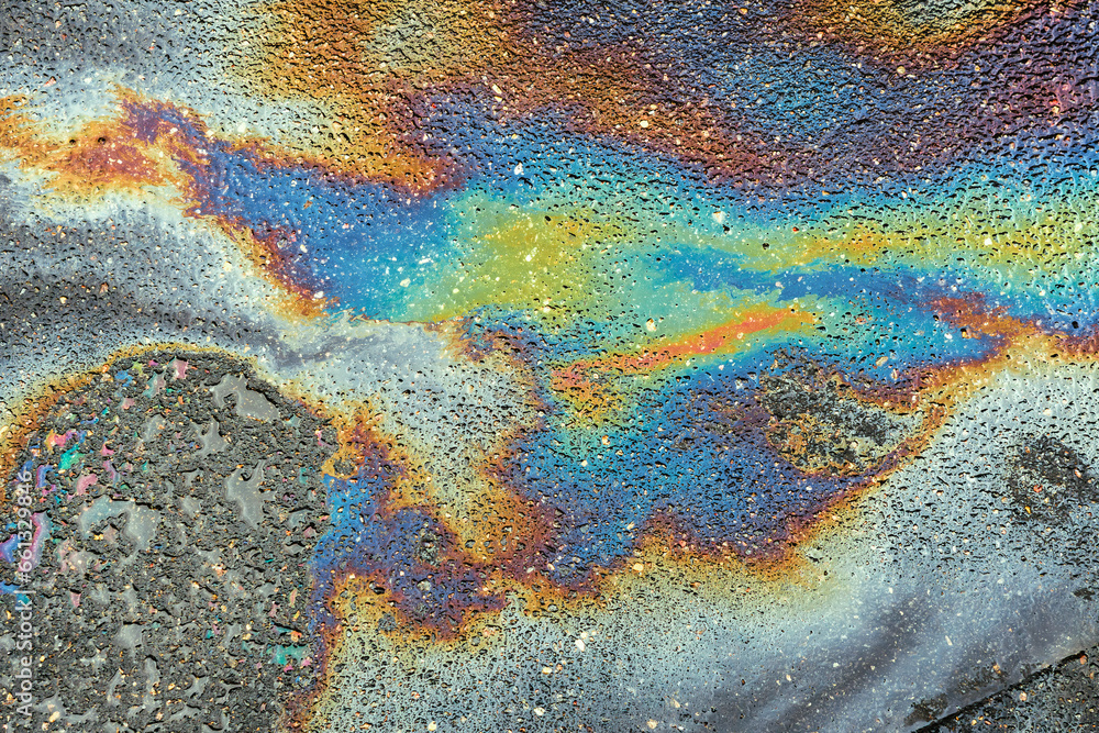 Colored oil stains close up, the color of the gasoline stain on the pavement road as a texture or background