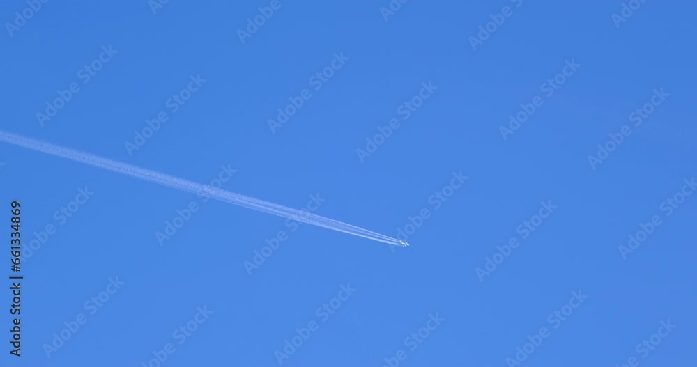 Airplane flying on deep blue sky with chemical direction trails, view from a distance Airplane flying on deep blue sky with chemical direction trails, view from a distance