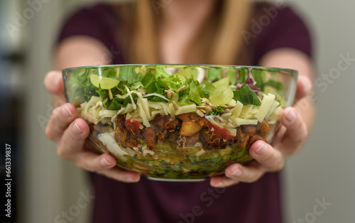 Kobieta trzyma szklaną salaterkę z sałatką warstwową