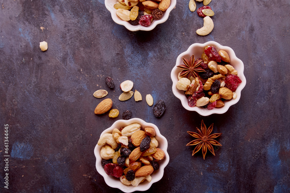Fototapeta premium Aesthetic saucers with mixed nuts close up. Walnuts, almonds, hazelnuts, cashew, raisins and cranberries. Healthy food and snacks.