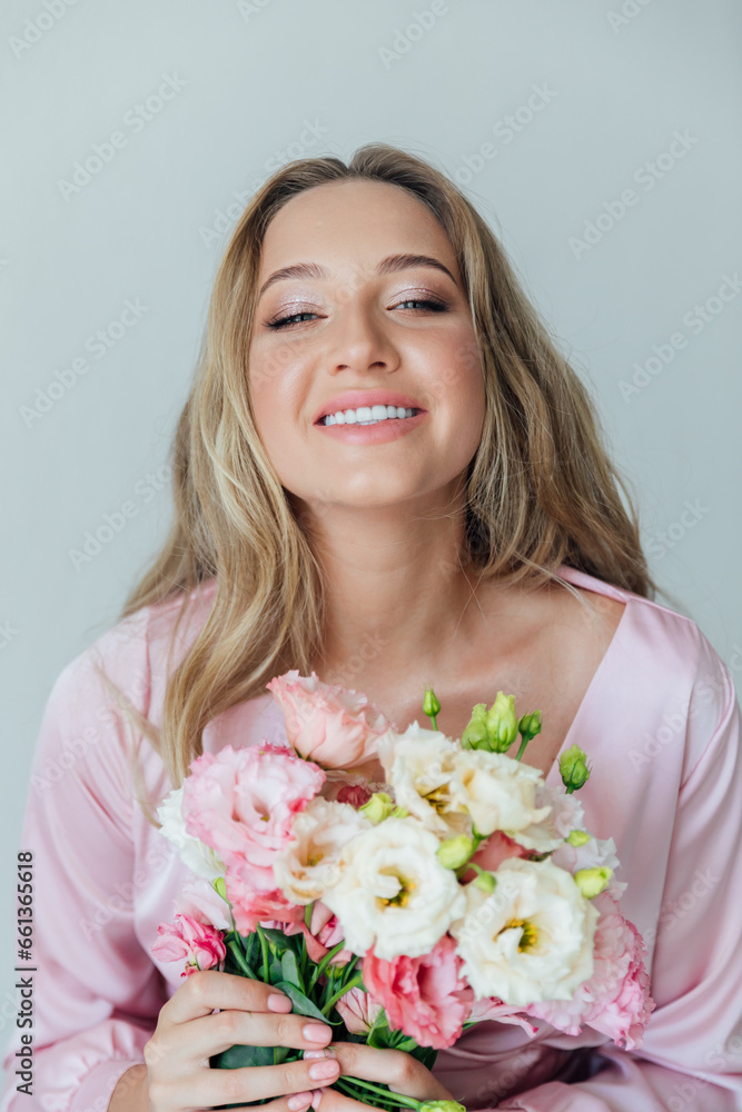 Beautiful woman in pink dress with flowers in the room for a holiday