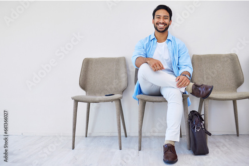 Smile, waiting and man in the office for recruitment meeting with human resources for hiring. Confidence, professional and person sitting on a chair for job interview in hallway in modern workplace.