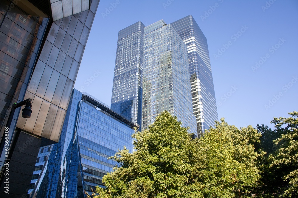 an area of buildings with trees in the foreground and blue sky