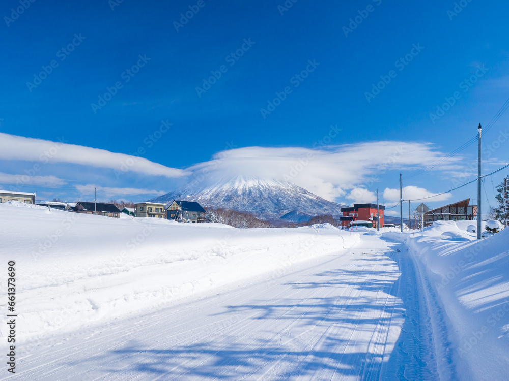 View of snowy volcano with a cap cloud beyond a heavy snowfall town (Niseko, Hokkaido, Japan)