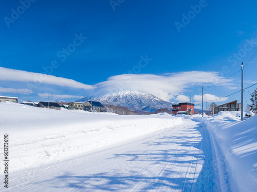 View of snowy volcano with a cap cloud beyond a heavy snowfall town (Niseko, Hokkaido, Japan) © Mayumi.K.Photography