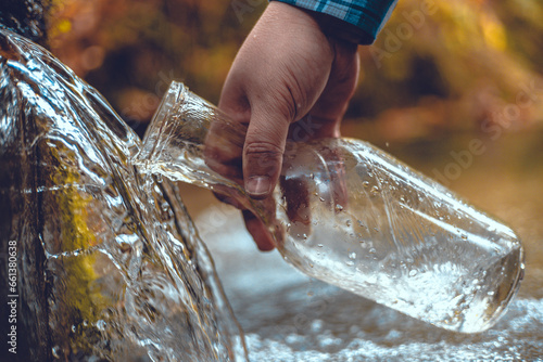 Fotografie Close-up of a man collecting spring water into a transparent bottle A beautiful natural source of clean drinking water