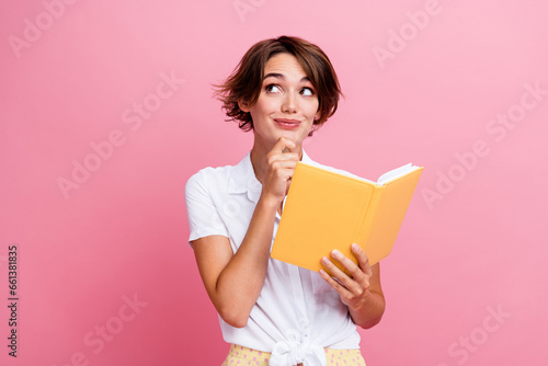 Portrait of smart young lady touch chin learning in university reading literature book looking minded isolated on pink color background