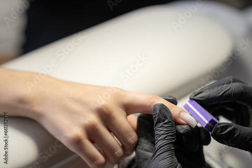 Female hands and tools for manicure  process of performing manicure in beauty salon. Nail care procedure in a beauty salon. Gloved hands of a skilled manicurist cutting cuticles. Concept spa body care