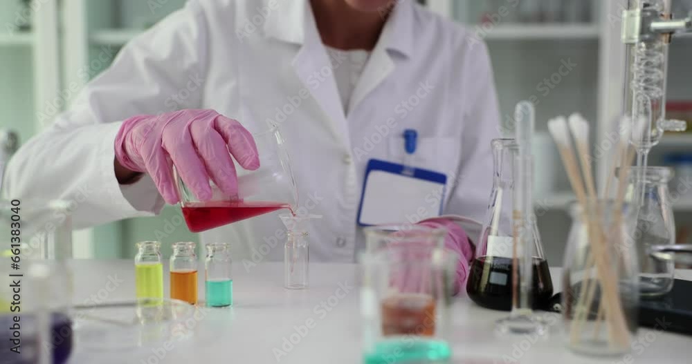 Scientist biologist pours red liquid into glass in laboratory. Toxic liquid examination Scientist biologist pours red liquid into glass in laboratory. Toxic liquid examination