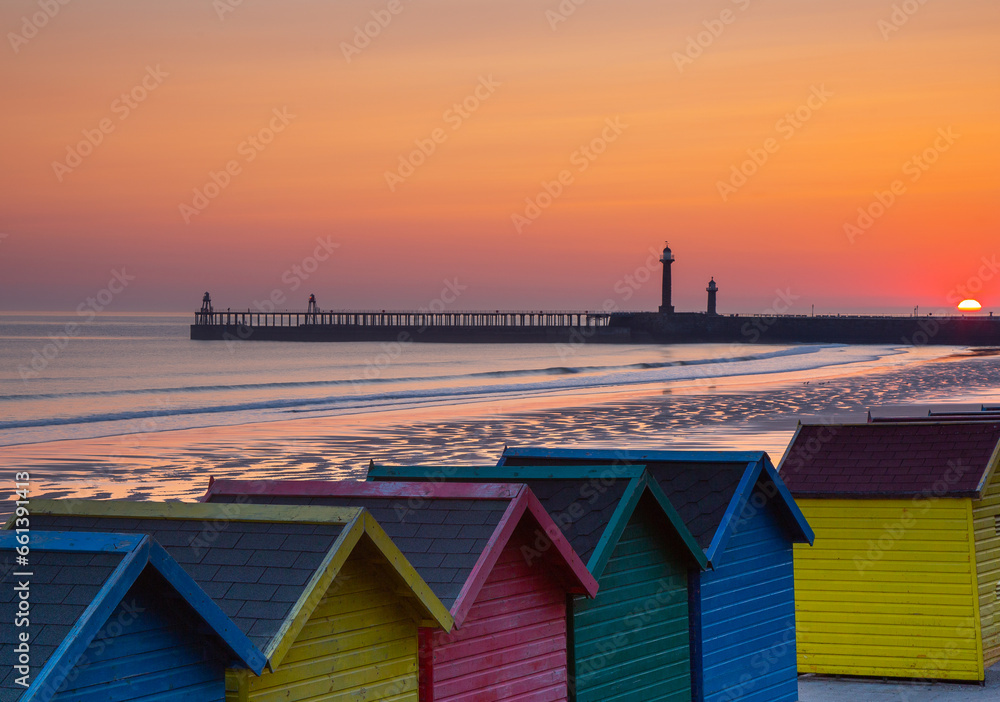 Whitby Pier and lighthouses with beach huts at sunrise