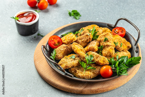 Homemade chicken nuggets with herbs and ketchup on a light background, top view