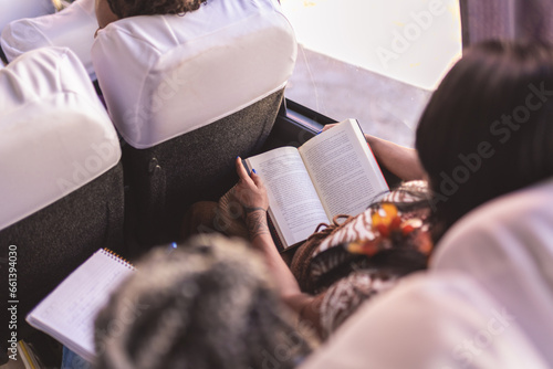 Jovem indigena lendo um livro durante uma viagem de onibus. Visao sobre o ombro. photo