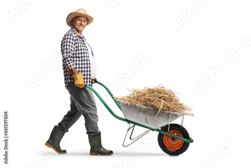 Valokuva Full length profile shot of a mature farmer pushing a wheelbarrow with a stack o