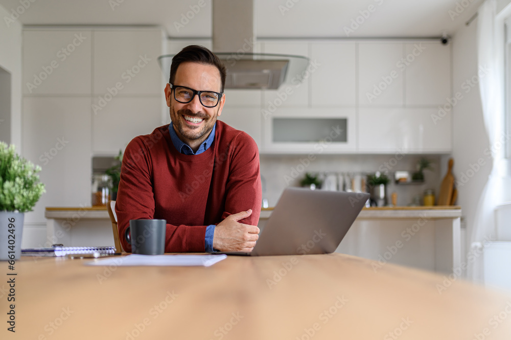 Portrait of confident businessman with laptop on desk looking at camera while working from home