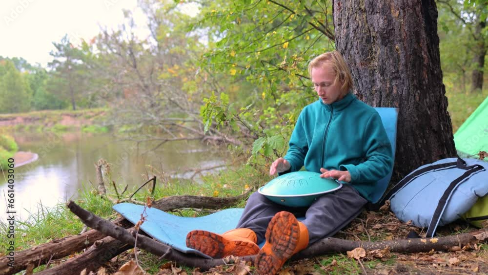 A musician plays the glucophone. A guy in an autumn park by the river. Percussion instrument on a journey through the forest A musician plays the glucophone. A guy in an autumn park by the river. Percussion instrument on a journey through the forest