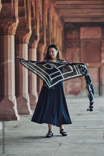 East asian woman in black dress dancing with translucent scarf among columns of ancient indian temple, touristic walking in Taj Mahal of attractive happy young girl, joyful tourism in India