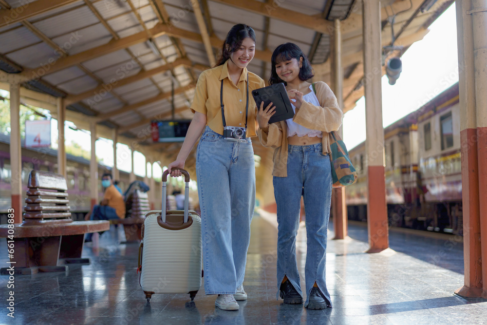 Two women are happy while traveling at the train station. tour concept.