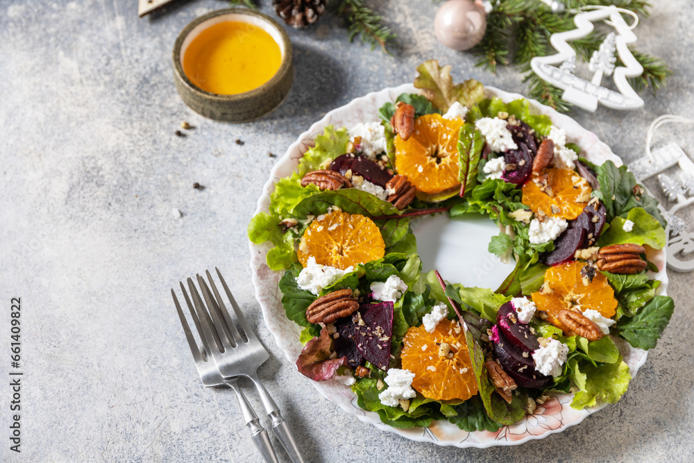 Christmas appetizer. Christmas wreath salad with beetroot, tangerines, feta cheese and pecans on the festive table. Copy space.