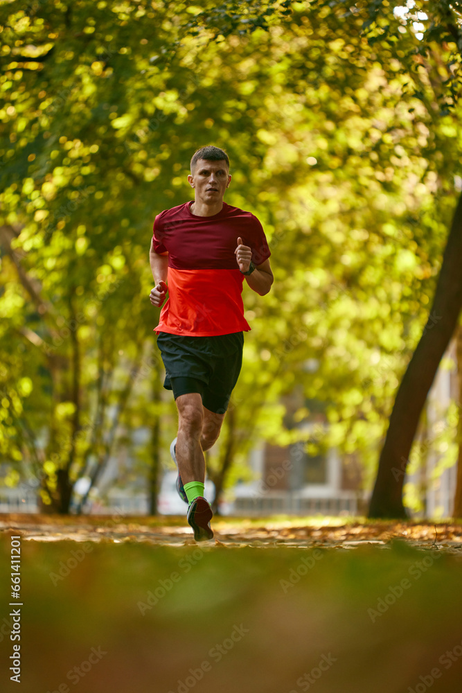 Dynamic image of man in sportswear, running, athlete in motion, training in city park. Preparation. Concept of sport, active and healthy lifestyle, competition, dynamics, marathon
