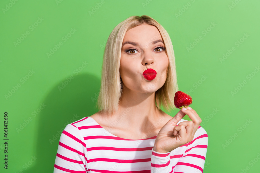 Photo of playful girlfriend young age lady eating sweet fresh strawberry fruit pouty lips cute air kiss isolated on green color background Photo of playful girlfriend young age lady eating sweet fresh strawberry fruit pouty lips cute air kiss isolated on green color background