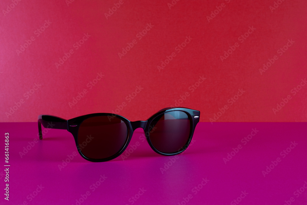 Designer Sunglasses on a Pink Surface with Red Background Designer Sunglasses on a Pink Surface with Red Background