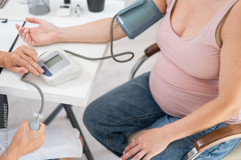 The doctor measures the pressure of a pregnant woman. The doctor measures the pressure of a pregnant woman.
