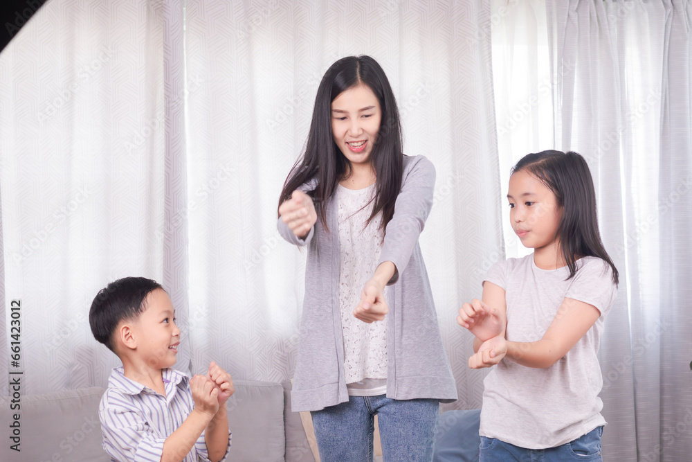 Happy family single mom dancing together with sibling children in living room at home, cheerful mother playing with little boy and girl kids exercise with music, healthy family bonding relationship Happy family single mom dancing together with sibling children in living room at home, cheerful mother playing with little boy and girl kids exercise with music, healthy family bonding relationship