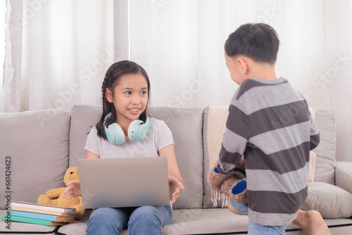 Asian sibling children play together bonding relationships on holiday at home, naughty boy kids are interested technology laptop want to watch video games while girl digital remote homeschool learning