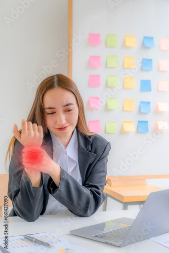 Successful business woman sitting in the meeting room Using a computer laptop to work so hard that it hurts her hand wrist's joint bone tendinitis, office syndrome concept