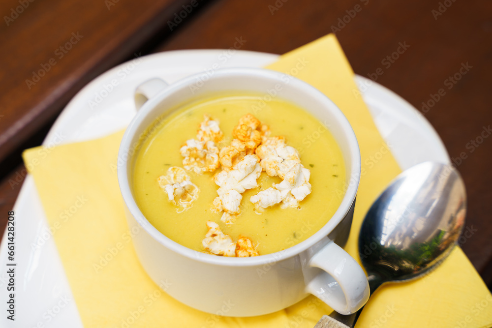 Bowl of sweet corn soup with popcorn on a wooden table Bowl of sweet corn soup with popcorn on a wooden table