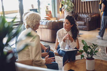 A hotel or travel agency representative is talking with a senior tourist couple offering various tourist services