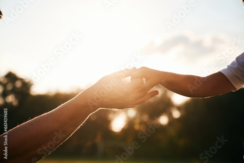 Beautiful sunlight. Close up view of dad and his little son hands that are holding each other