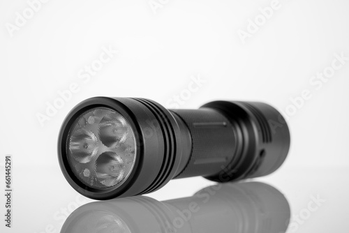 black LED modern handheld flashlight on a white background with reflection, metal durable housing, double-sided, led flashlight, reflexed pen, studio photo