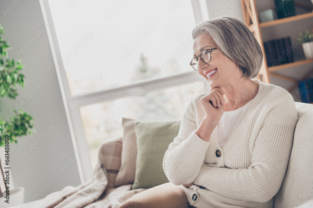 Photo of pretty adorable senior lady dressed white cardigan sitting sofa watching movie indoors house room Photo of pretty adorable senior lady dressed white cardigan sitting sofa watching movie indoors house room