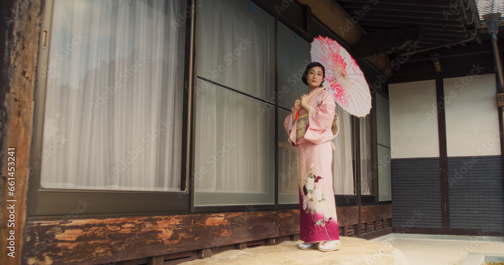 Portrait of a Lovely Female in a Pink Traditional Dress Turning From Side to Side, Changing Positions while Looking at Camera. Elegant Young Woman in a Kimono Posing Outside an Old Shrine