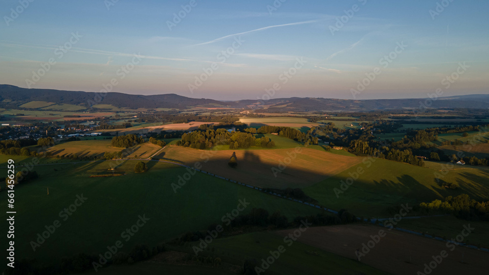 Landscape of czech mountains with meadows and forests during sunrise.