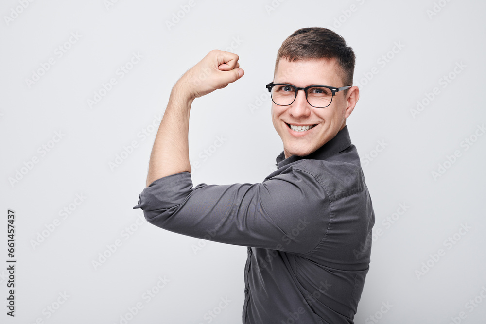 Portrait of confident young man showing biceps, demonstrating strength isolated on white studio background. Lucky winner concept Portrait of confident young man showing biceps, demonstrating strength isolated on white studio background. Lucky winner concept