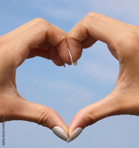 joined hands forming the shape of a heart and the background of the blue sky