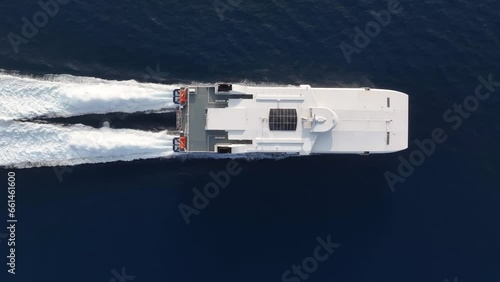 Aerial top down tracking view of a catamaran jet passenger ferry boat traveling with high speed over the ocean photo