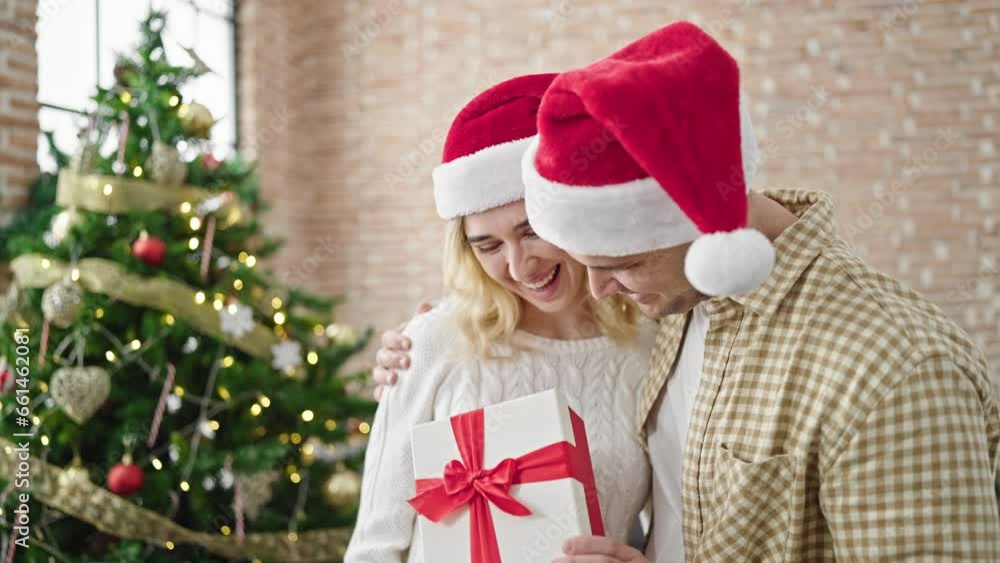 Man and woman couple hugging each other holding christmas gift at home Man and woman couple hugging each other holding christmas gift at home