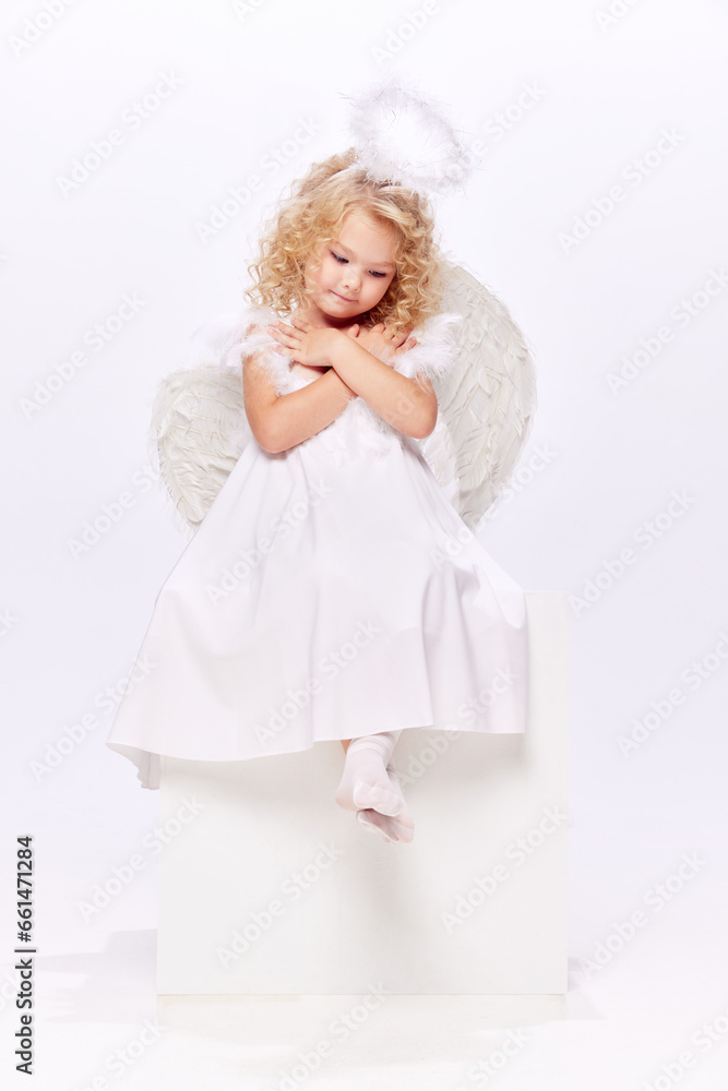 Beautiful cute little girl, child in image of angel, wearing white dress and halo isolated over white studio background. Concept of childhood, imagination, fantasy, fashion and beauty, holidays Beautiful cute little girl, child in image of angel, wearing white dress and halo isolated over white studio background. Concept of childhood, imagination, fantasy, fashion and beauty, holidays