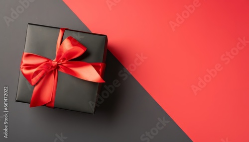 Top view of black giftbox with red ribbon on two color red and black background with copy space