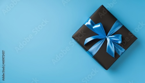 Top view of black giftbox with blue ribbon on blue background with empty space © Loliruri